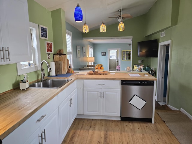 kitchen featuring stainless steel dishwasher, lofted ceiling, wooden counters, light wood-type flooring, and a sink