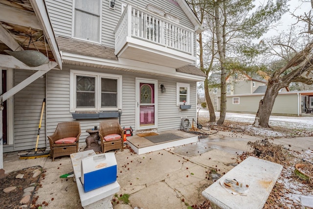 doorway to property with roof with shingles, a patio area, and a balcony