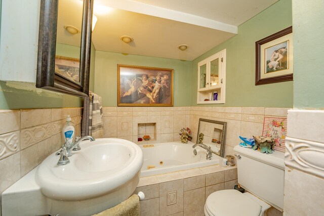 full bath featuring a jetted tub, tile walls, toilet, and a sink