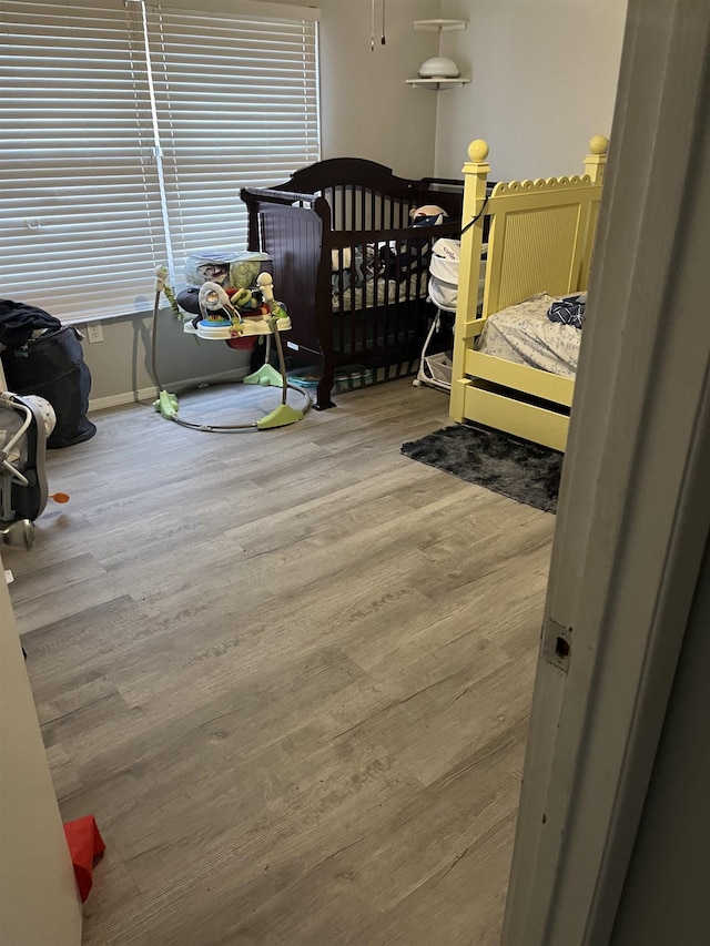 bedroom with hardwood / wood-style floors and a nursery area