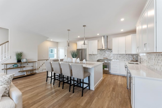 kitchen featuring white cabinetry, high end appliances, a center island, and wall chimney range hood