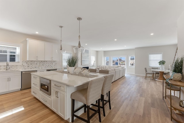 kitchen with a kitchen island, appliances with stainless steel finishes, decorative light fixtures, white cabinetry, and sink