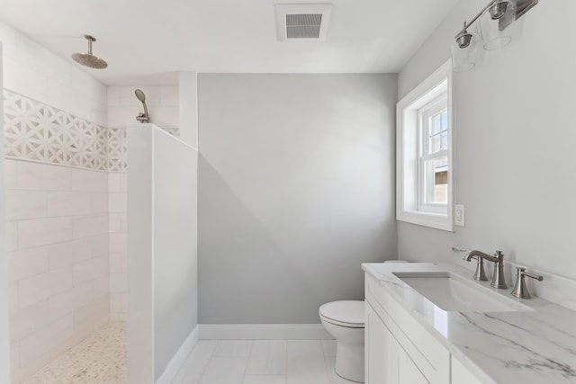 bathroom with vanity, a tile shower, and toilet