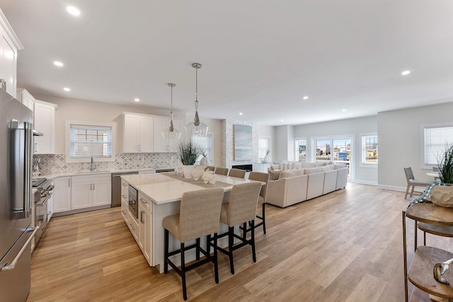 kitchen featuring pendant lighting, a kitchen breakfast bar, a center island, and white cabinets