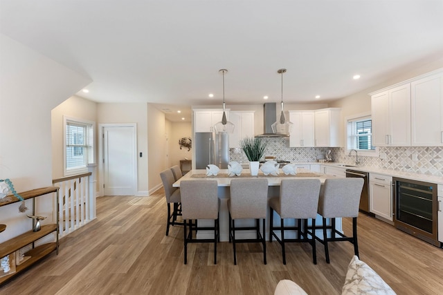 kitchen featuring appliances with stainless steel finishes, wall chimney exhaust hood, a center island, and hanging light fixtures