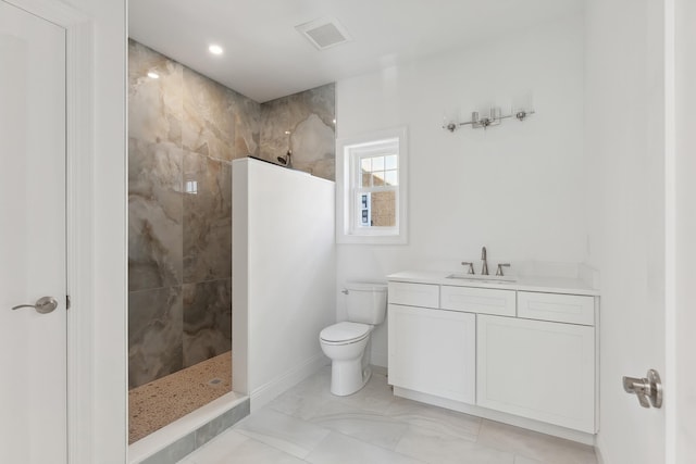 bathroom with vanity, toilet, and tiled shower