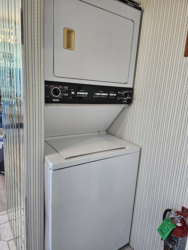 clothes washing area featuring stacked washer and dryer and light tile patterned flooring