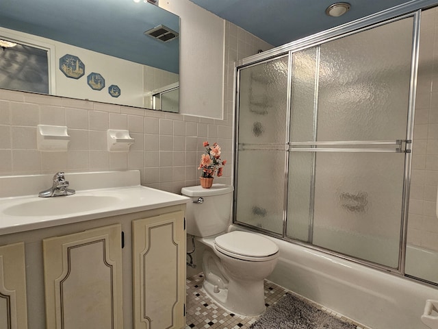 full bathroom featuring tile walls, tile patterned flooring, bath / shower combo with glass door, vanity, and toilet