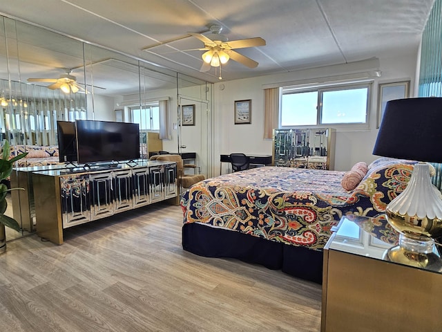 bedroom featuring multiple windows, hardwood / wood-style flooring, and ceiling fan