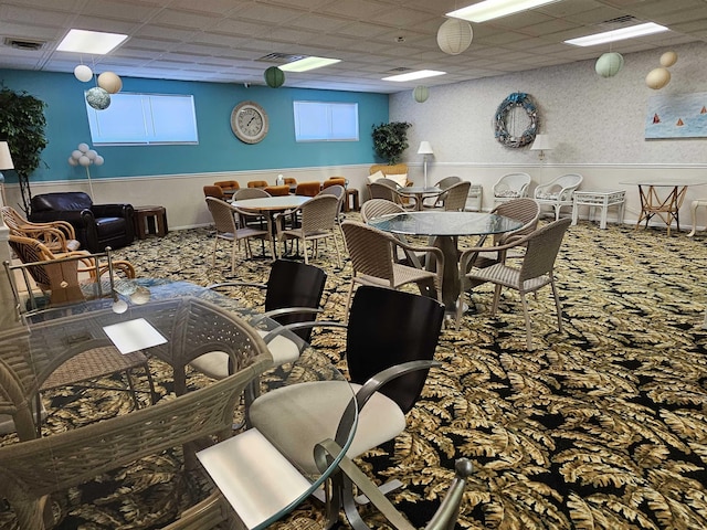 carpeted dining space featuring a paneled ceiling