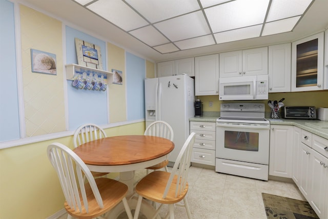 kitchen with white appliances, white cabinets, a paneled ceiling, and light tile patterned flooring