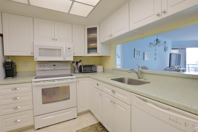 kitchen featuring an inviting chandelier, light tile patterned floors, white cabinetry, white appliances, and sink