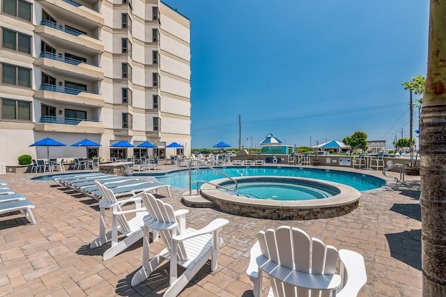 view of pool with a hot tub and a patio