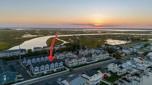 aerial view at dusk featuring a water view