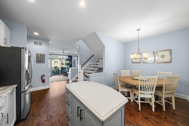 kitchen with a center island, dark wood-type flooring, ceiling fan with notable chandelier, hanging light fixtures, and stainless steel refrigerator