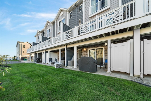 rear view of house featuring a yard, a balcony, central AC unit, and a patio area