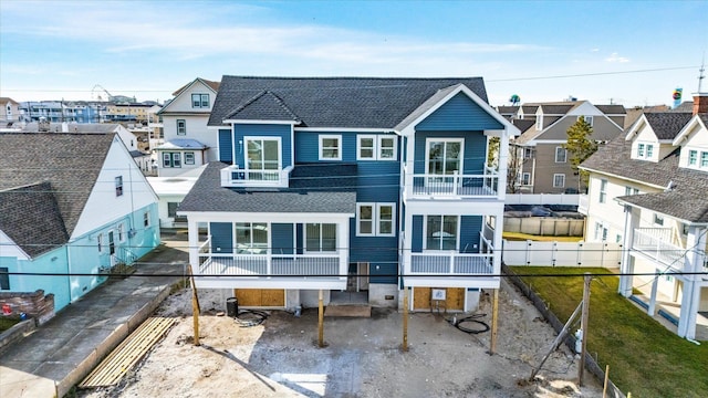 back of property featuring a residential view, a fenced backyard, a balcony, and roof with shingles