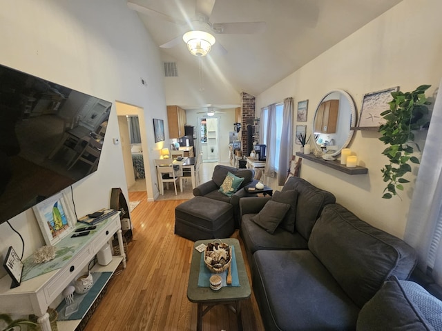 living room featuring light hardwood / wood-style flooring, high vaulted ceiling, and ceiling fan