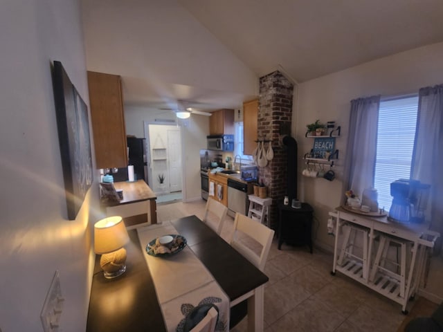 tiled dining space with vaulted ceiling, ceiling fan, and a wood stove