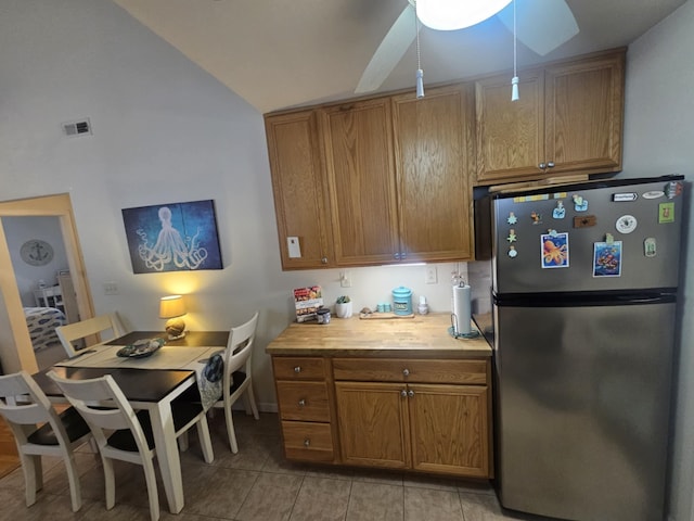 kitchen with stainless steel fridge, vaulted ceiling, and light tile patterned floors