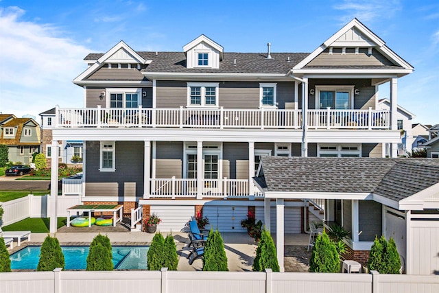 view of front of home featuring a patio area, a balcony, and a fenced in pool