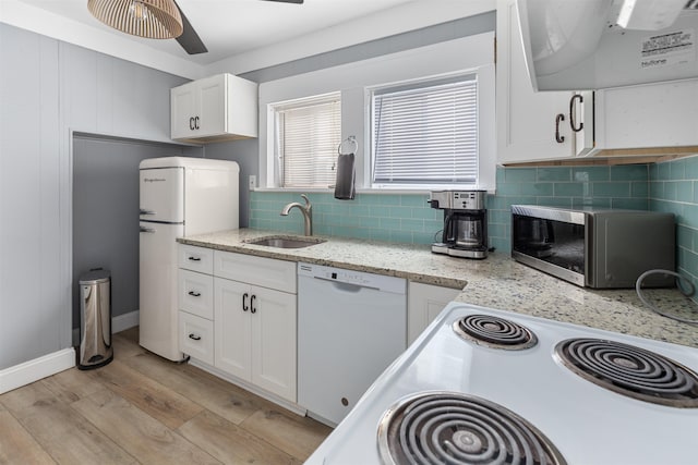 kitchen featuring white appliances, white cabinets, a sink, light wood-type flooring, and backsplash