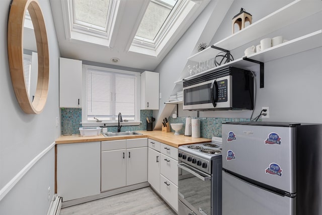 kitchen with appliances with stainless steel finishes, a sink, white cabinetry, wooden counters, and backsplash