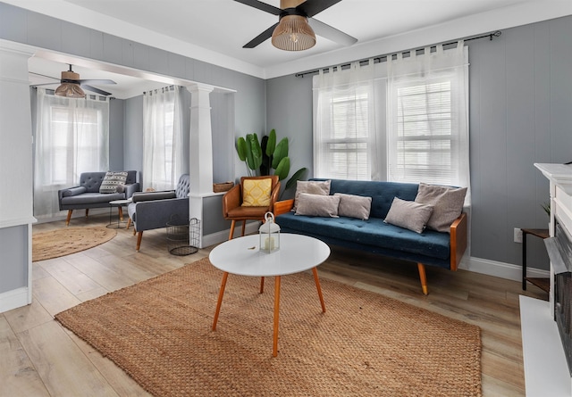 living room with ceiling fan, light wood finished floors, decorative columns, and baseboards