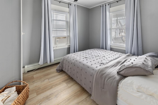 bedroom featuring light wood-type flooring, a baseboard radiator, multiple windows, and cooling unit