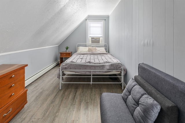 bedroom featuring lofted ceiling, a textured ceiling, a baseboard radiator, wood finished floors, and baseboards