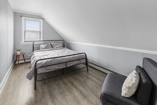 bedroom with lofted ceiling, a baseboard heating unit, and wood finished floors