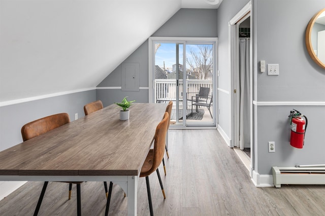 dining space featuring light wood-type flooring, a baseboard radiator, baseboards, and vaulted ceiling