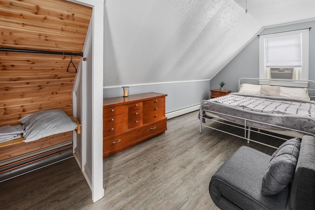 bedroom with lofted ceiling, a textured ceiling, a baseboard radiator, and wood finished floors