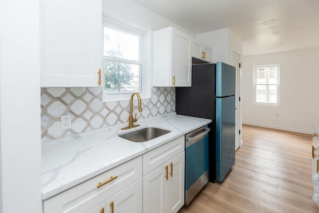 kitchen featuring white cabinets, a sink, light stone countertops, light wood-type flooring, and dishwasher