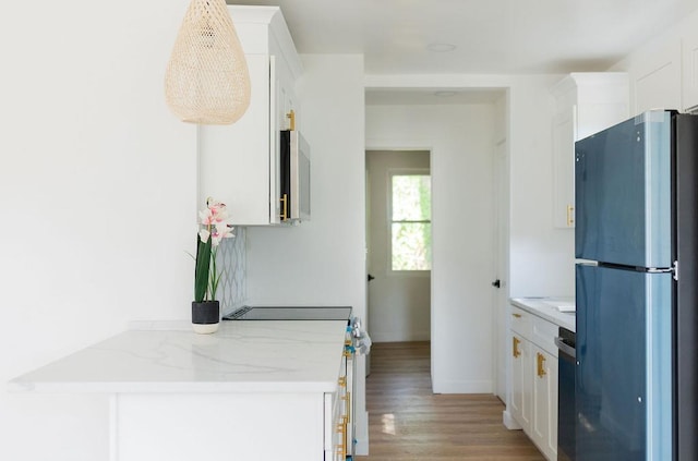 kitchen featuring stainless steel appliances, light wood-type flooring, white cabinetry, and light stone counters