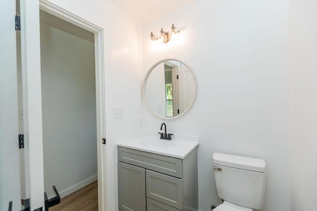 bathroom featuring baseboards, vanity, toilet, and wood finished floors