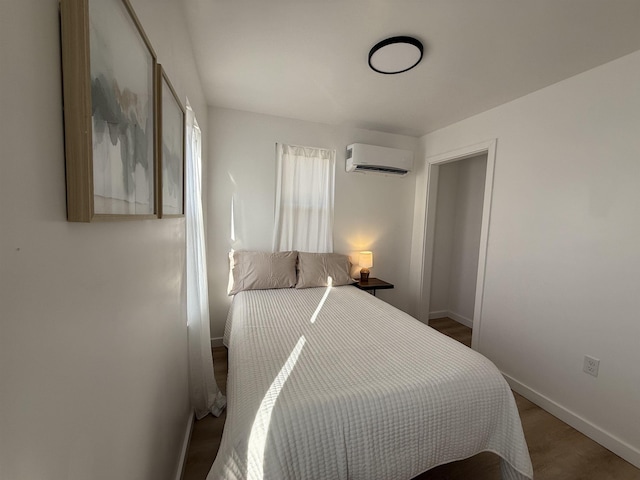 bedroom featuring an AC wall unit, baseboards, and wood finished floors