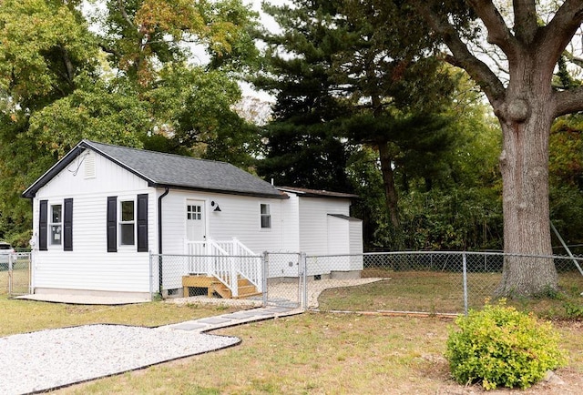 view of side of property with a shingled roof, a gate, fence, and a lawn