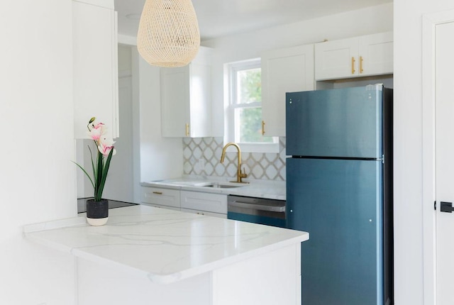 kitchen with tasteful backsplash, appliances with stainless steel finishes, light stone countertops, white cabinetry, and a sink