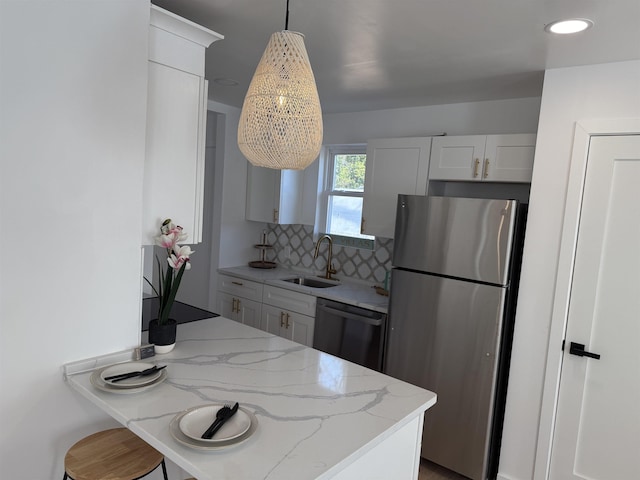 kitchen with light stone counters, black dishwasher, backsplash, freestanding refrigerator, and a sink