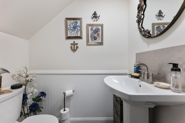 bathroom featuring sink, toilet, decorative backsplash, and lofted ceiling