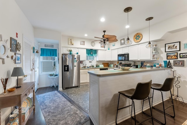 kitchen with kitchen peninsula, stainless steel refrigerator with ice dispenser, decorative light fixtures, and white cabinets