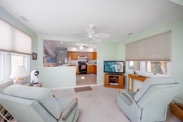 living room with light carpet, a ceiling fan, visible vents, and baseboards