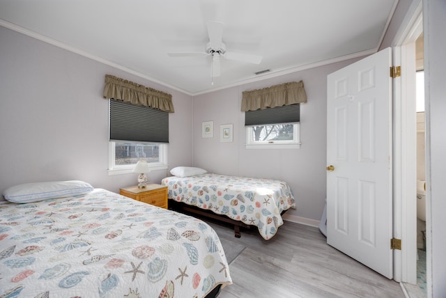 bedroom with light wood-style flooring, visible vents, and crown molding