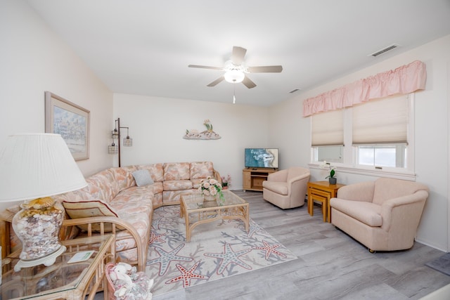 living room with ceiling fan, visible vents, and wood finished floors