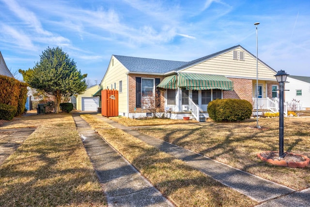 bungalow-style home with an outbuilding, brick siding, a front lawn, and a detached garage