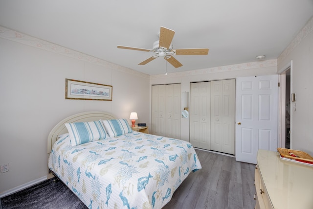 bedroom with baseboards, ceiling fan, wood finished floors, and multiple closets