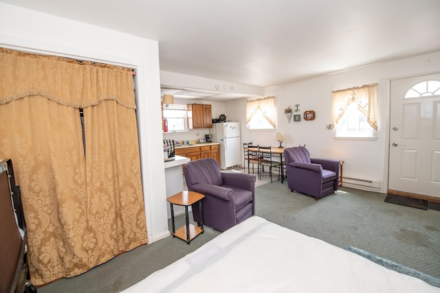 interior space with a baseboard heating unit, white refrigerator, dark colored carpet, and multiple windows