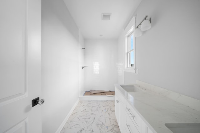 full bath with marble finish flooring, vanity, and a shower