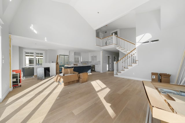 living room featuring high vaulted ceiling and light hardwood / wood-style flooring